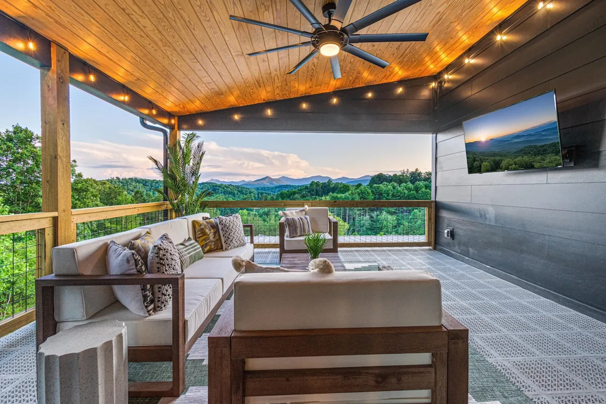 A welcoming exterior seating area that overlooks rolling mountains, featuring comfortable lounge furniture and ambient lighting. The scene suggests relaxation after a day spent outdoors, with views that hint at the natural wonders waiting to be explored.